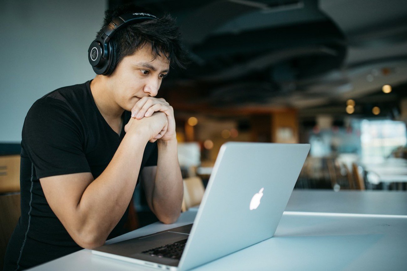 A learner with headphones working through a course on a laptop